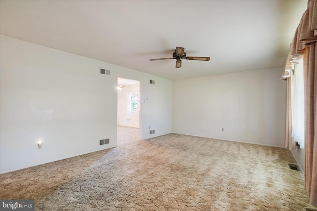 spare room featuring carpet floors, ceiling fan, and visible vents