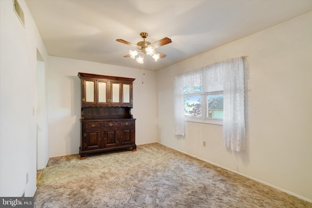 carpeted empty room featuring ceiling fan, visible vents, and baseboards