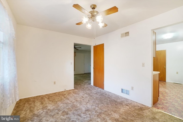 empty room with ceiling fan, light colored carpet, and visible vents