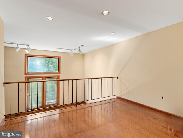 unfurnished room with recessed lighting, rail lighting, baseboards, and wood finished floors