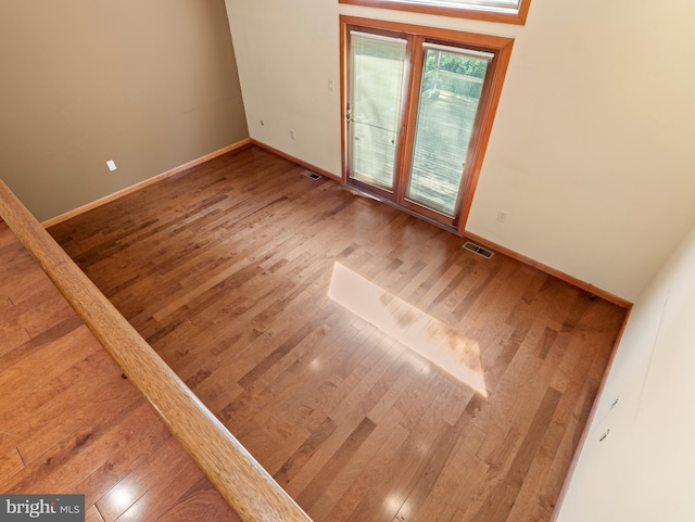 spare room featuring baseboards, wood finished floors, and visible vents