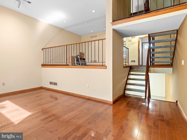 unfurnished room with visible vents, stairway, baseboards, wood-type flooring, and recessed lighting