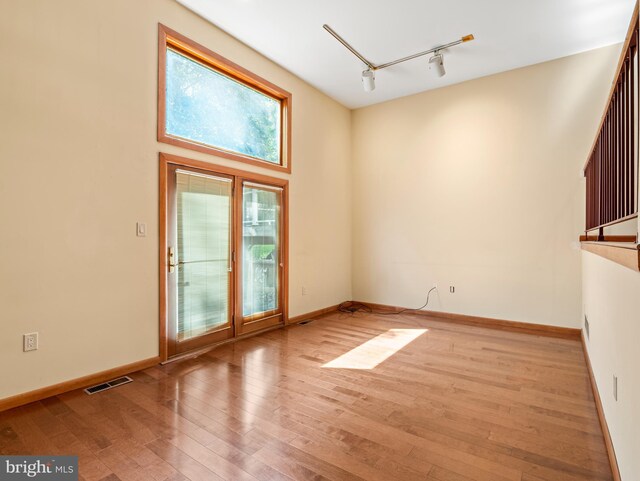 spare room featuring track lighting, baseboards, hardwood / wood-style floors, and visible vents