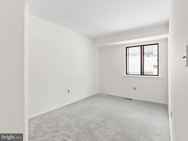empty room featuring carpet flooring, baseboards, and visible vents