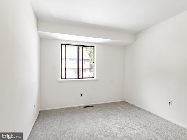 spare room featuring carpet floors, baseboards, and visible vents