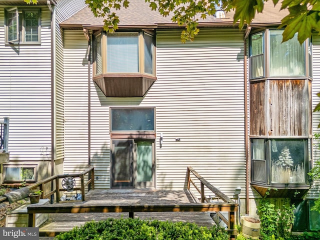 rear view of property featuring a deck and roof with shingles