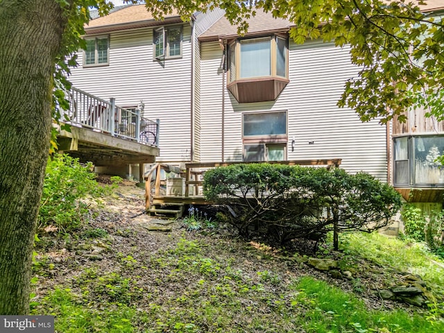 back of house featuring a wooden deck and a shingled roof