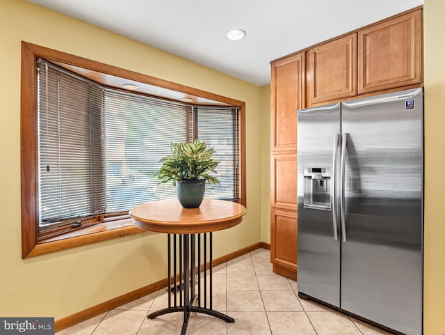 kitchen featuring brown cabinets, stainless steel fridge with ice dispenser, recessed lighting, baseboards, and light tile patterned floors