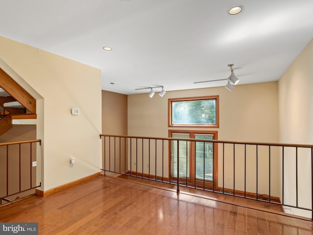 spare room with recessed lighting, rail lighting, baseboards, and hardwood / wood-style flooring