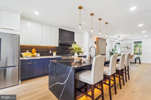 kitchen featuring freestanding refrigerator, a breakfast bar, custom exhaust hood, light wood-type flooring, and recessed lighting