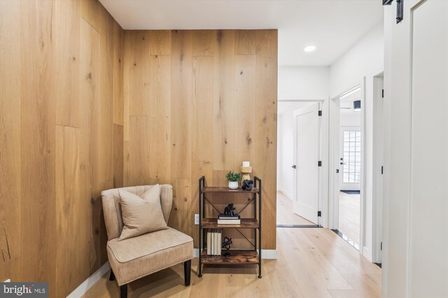 living area featuring wood finished floors, wooden walls, a barn door, and recessed lighting