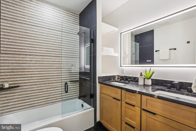 full bath featuring bath / shower combo with glass door and double vanity