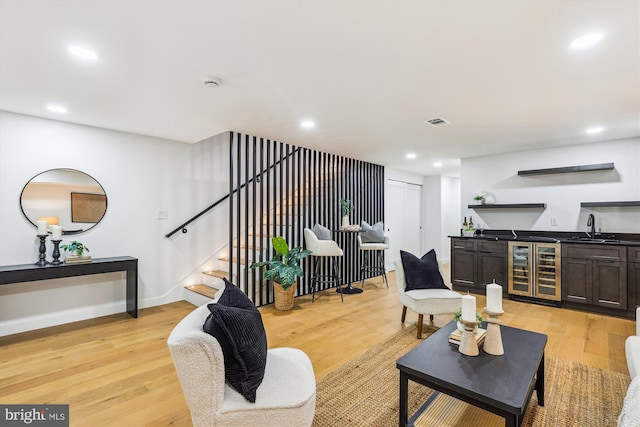 living room with bar with sink, wine cooler, light wood-type flooring, stairway, and recessed lighting