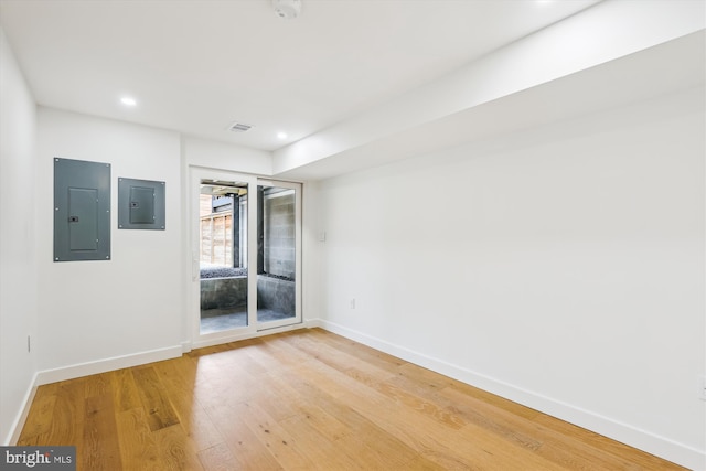 unfurnished room with electric panel, baseboards, light wood-type flooring, and recessed lighting