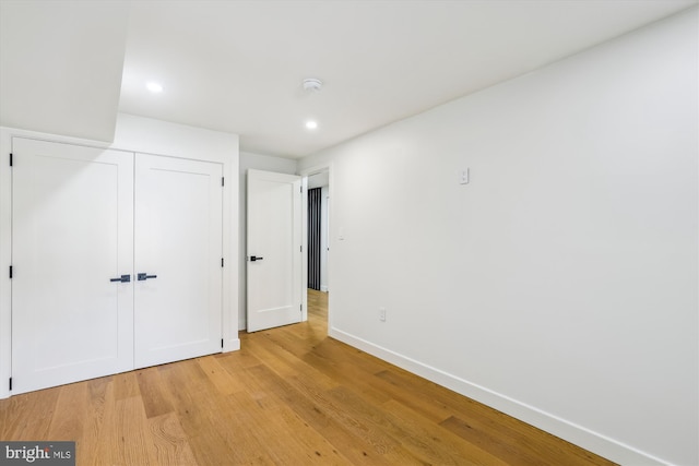 unfurnished bedroom with light wood-style flooring, baseboards, a closet, and recessed lighting