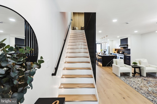 stairs featuring wood finished floors and recessed lighting