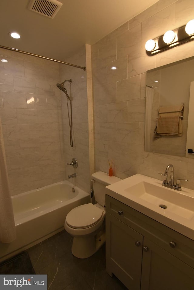 full bathroom featuring tile walls, toilet, vanity, visible vents, and shower / tub combo