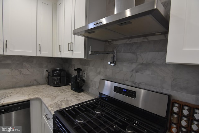 kitchen featuring white cabinetry, stainless steel appliances, backsplash, and wall chimney exhaust hood