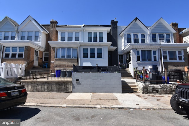 townhome / multi-family property with brick siding and a fenced front yard