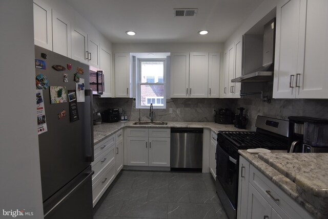 kitchen with a sink, stainless steel appliances, wall chimney exhaust hood, visible vents, and white cabinets