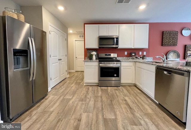 kitchen with white cabinetry, stainless steel appliances, light wood-style flooring, and a sink