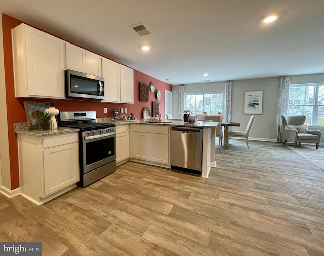 kitchen featuring visible vents, white cabinets, appliances with stainless steel finishes, and a wealth of natural light