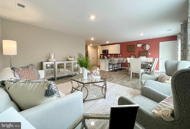 living room with visible vents, recessed lighting, and light wood-style flooring