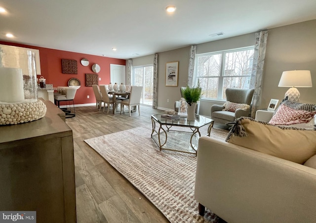 living area featuring baseboards, recessed lighting, wood finished floors, and a healthy amount of sunlight