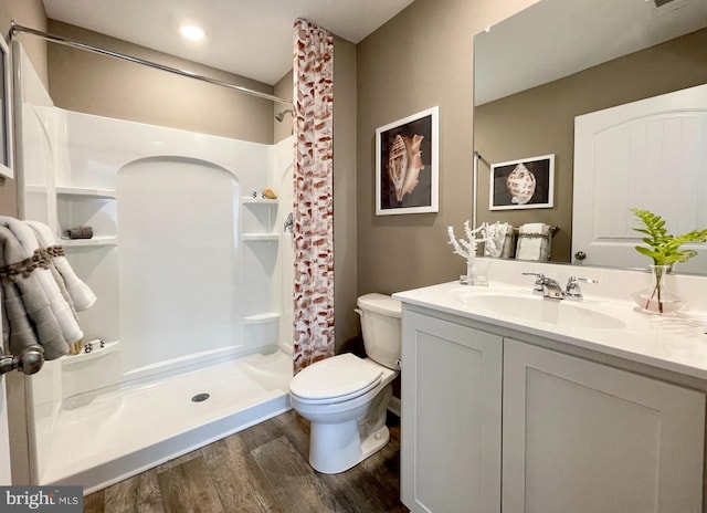 full bathroom with a stall shower, toilet, wood finished floors, and vanity