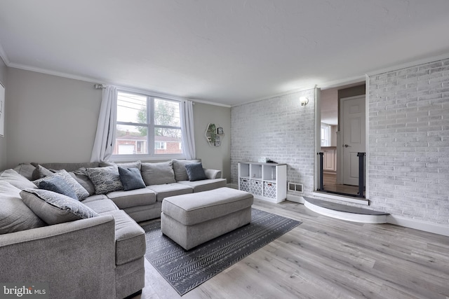 living room featuring light wood-type flooring, brick wall, and crown molding