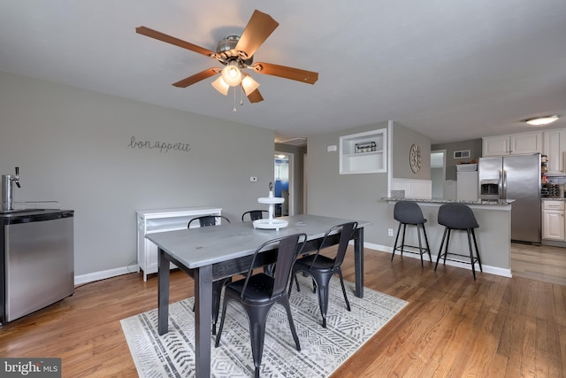 dining space featuring baseboards, a ceiling fan, and light wood-style flooring