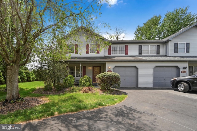traditional home featuring an attached garage, driveway, and a front yard