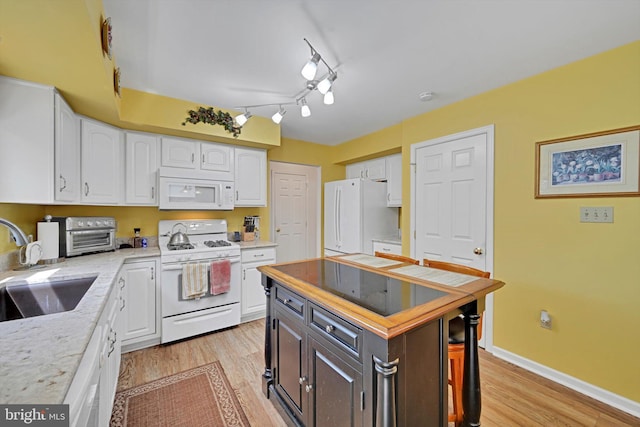 kitchen with white appliances, white cabinets, a sink, and light wood finished floors
