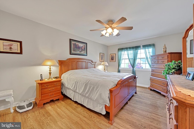 bedroom with a ceiling fan, baseboards, and light wood-style flooring