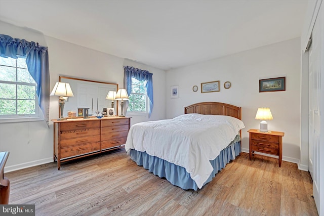 bedroom with light wood-type flooring, baseboards, and multiple windows