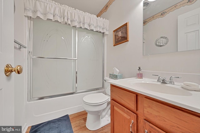 bathroom featuring toilet, combined bath / shower with glass door, wood finished floors, and vanity