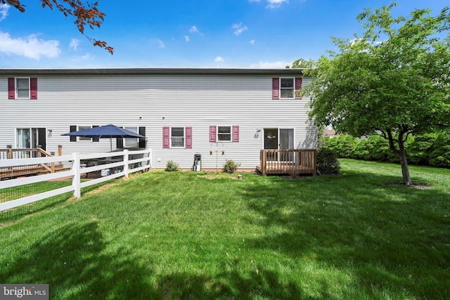 rear view of property featuring fence and a yard