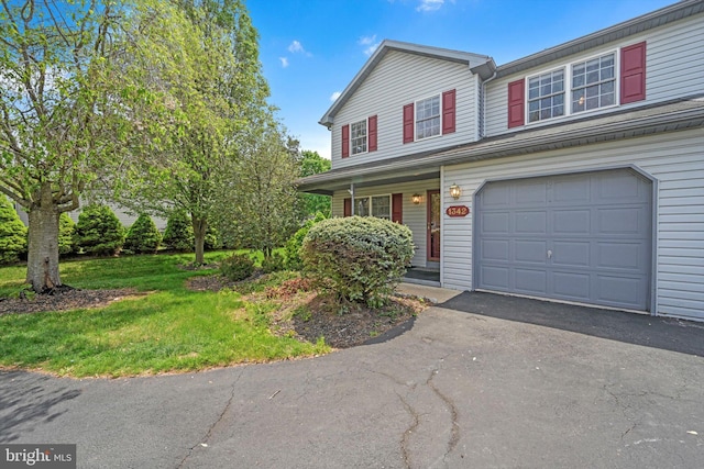 traditional-style house with a porch, an attached garage, driveway, and a front yard