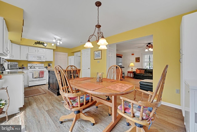 dining area with light wood finished floors, ceiling fan, and a toaster