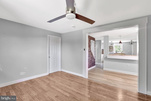 unfurnished living room featuring stairs, a ceiling fan, baseboards, and wood finished floors