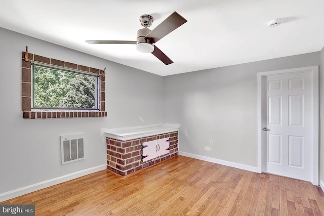spare room with visible vents, a ceiling fan, baseboards, and wood finished floors