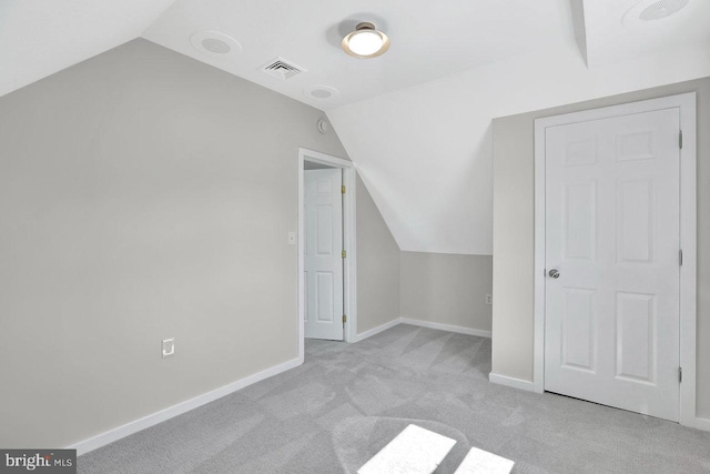additional living space with visible vents, baseboards, vaulted ceiling, and carpet