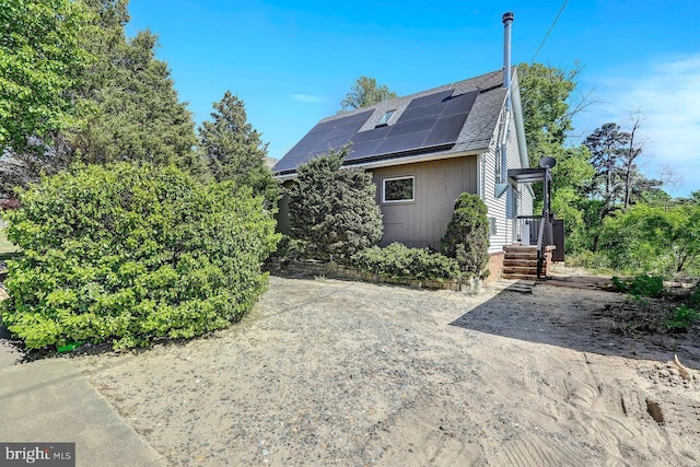 exterior space with roof mounted solar panels and roof with shingles