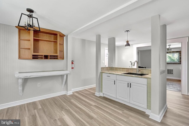 kitchen with a sink, a chandelier, baseboards, light wood-type flooring, and visible vents