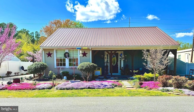 bungalow-style home featuring fence, metal roof, and a porch