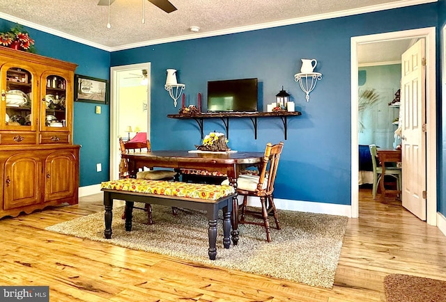 dining area featuring a textured ceiling, wood finished floors, a ceiling fan, and ornamental molding