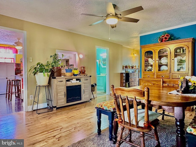 dining space with a textured ceiling, a ceiling fan, and ornamental molding