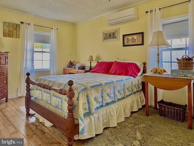 bedroom with a textured ceiling, wood finished floors, a wall unit AC, and crown molding
