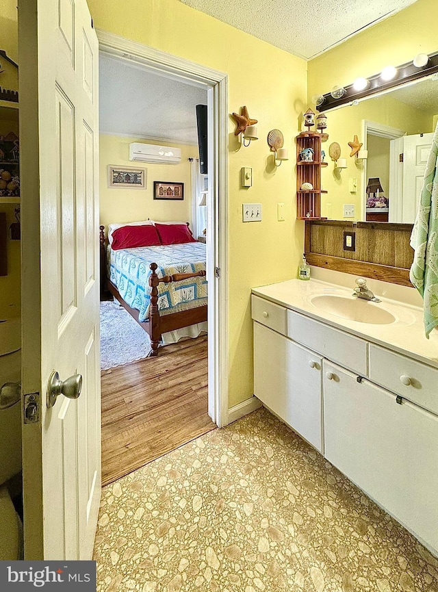 bathroom with a textured ceiling, vanity, and an AC wall unit