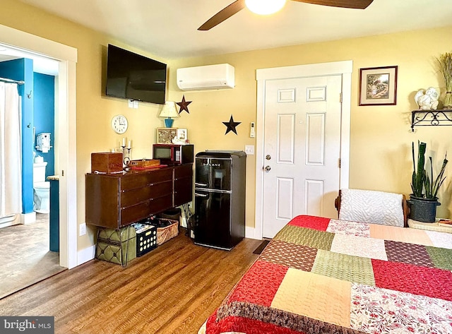 bedroom featuring wood finished floors, ceiling fan, a wall unit AC, and baseboards